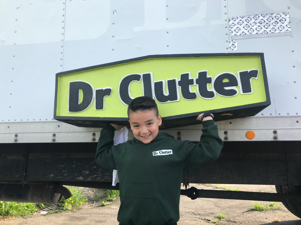 Dr Clutter crew member holding sign in front of junk removal truck